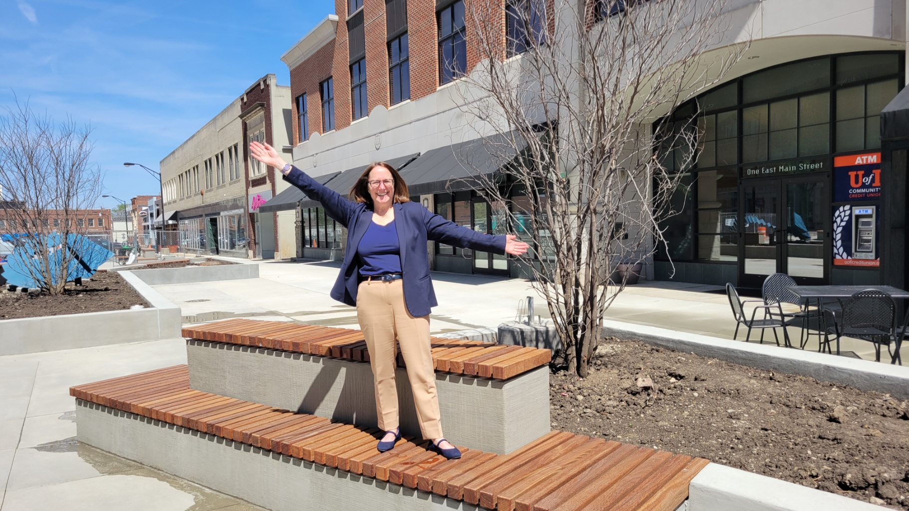 Mayor Deb Feinen stands on a tiered bench and poses as Mary Tyler Moore 