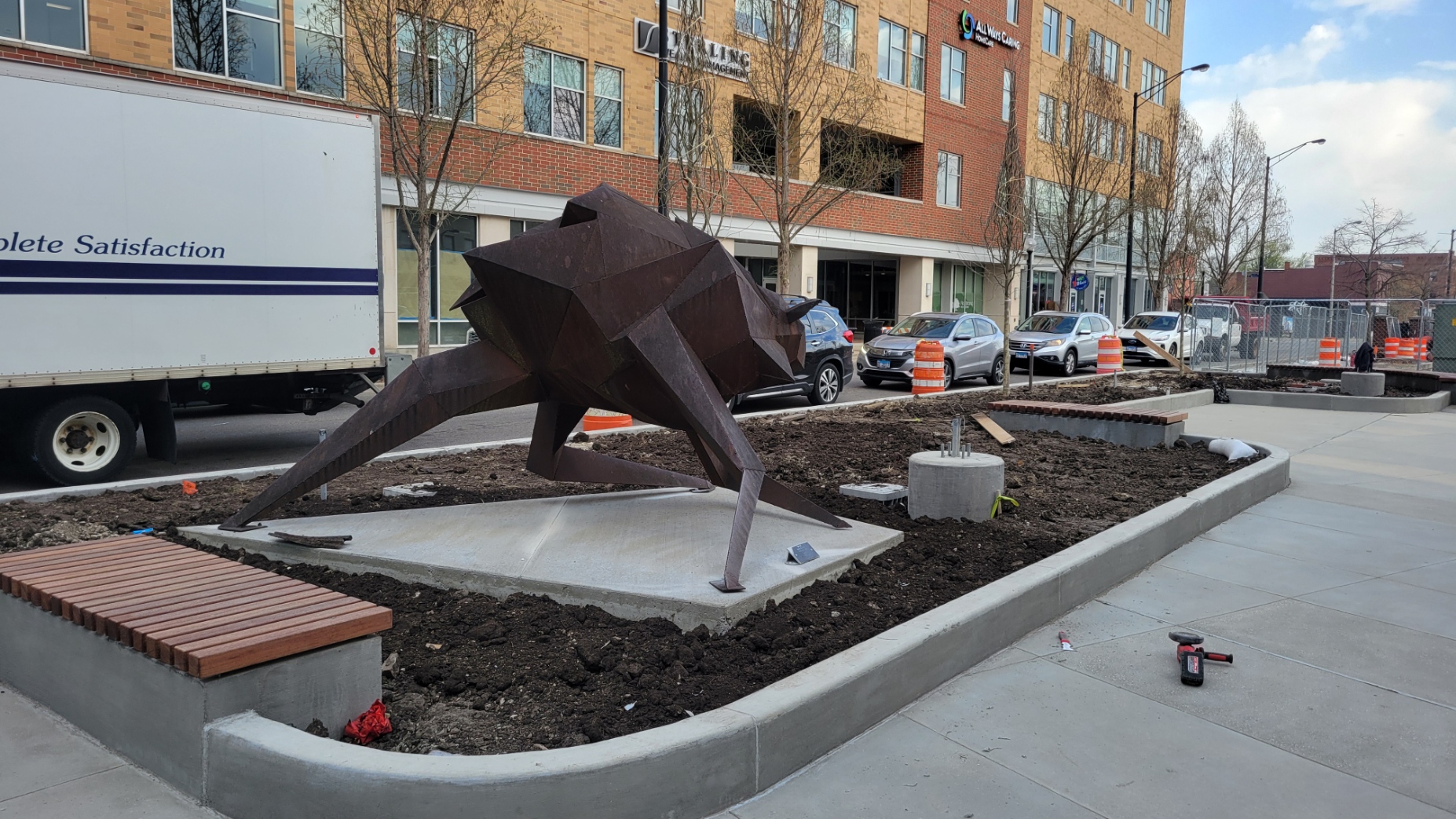An anthropomorphized public art sculpture is pictured in a planter on the west side of the plaza facing north, just east of Neil Stret.