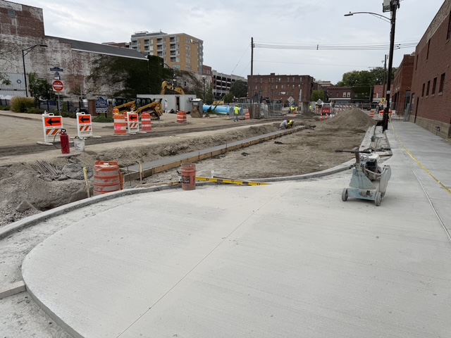 A photo of Washington at Fremont, facing west, showing newly poured concrete sidewalks with curb bumpouts and an excavated roadway open for stormwater pipes and water main installation.
