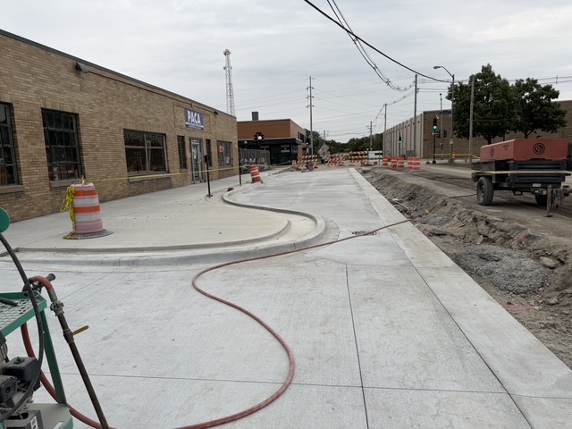 A photo of Washington, facing east, at Fremont showing newly poured concrete sidewalks and an on-street parking aisle. The excavated roadway also shows the difference in grades; the new roadway will be lower and have improved stormwater infrastructure to 