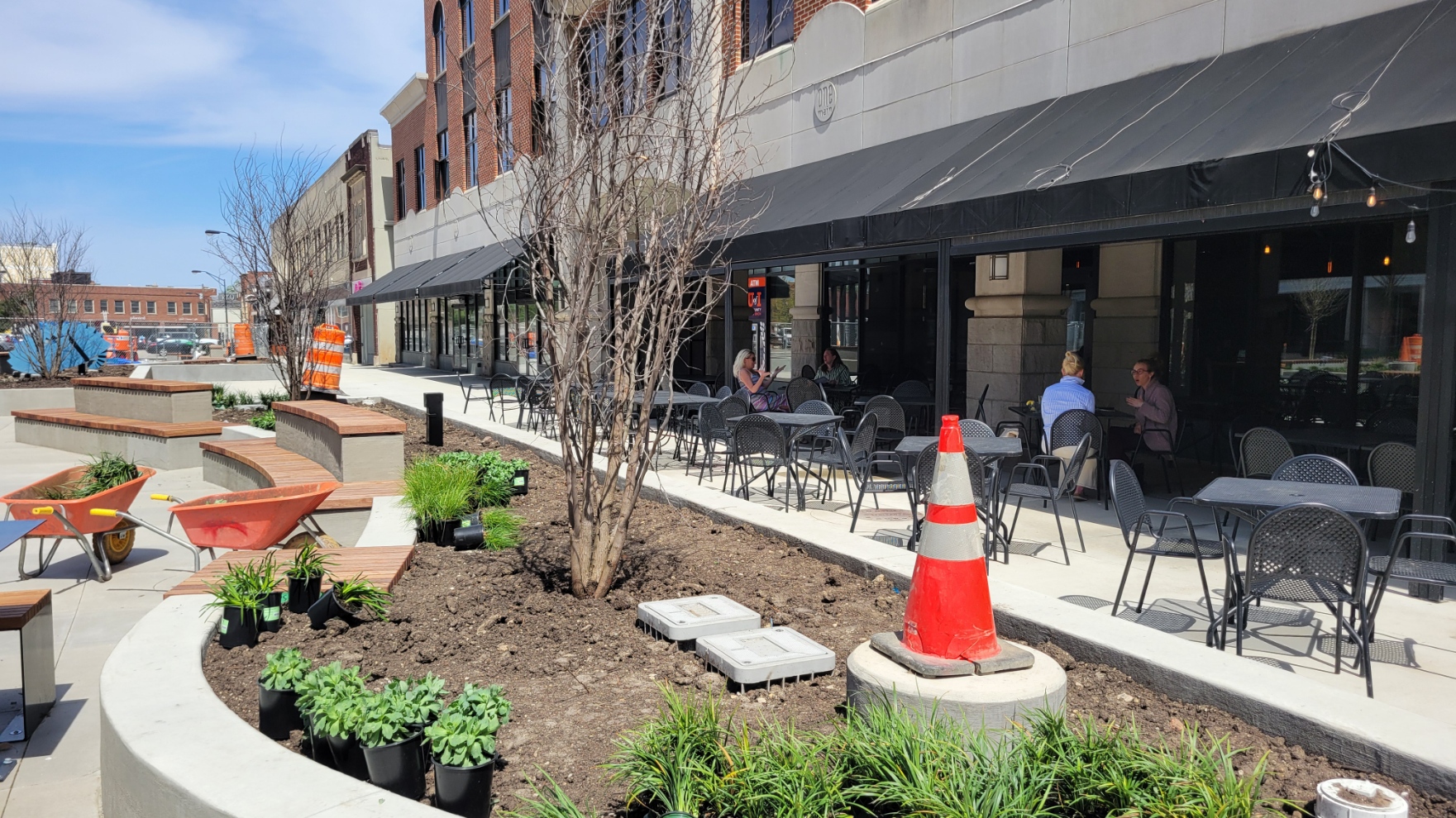A view of a planter bed in the plaza with several groundcover plants in pots, soon to be planted.